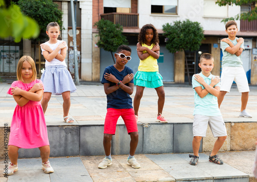 International group of modern tweenagers performing street dance choreography outdoors in summer..