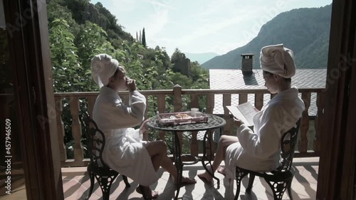Two women having breakfast outdoors on the balcony. Romantic getaway in the mountains of Spain for vacation. Homosexual lesbian couple having a good time together.