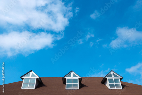 Three windows on a roof of house with a beautiful sky and cloud background © Gatot