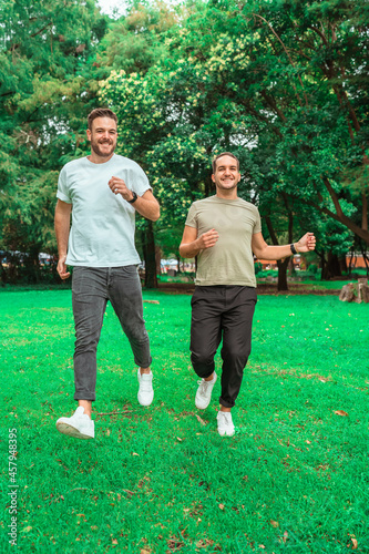 Fototapeta Naklejka Na Ścianę i Meble -  gay couple running on the grass in a park