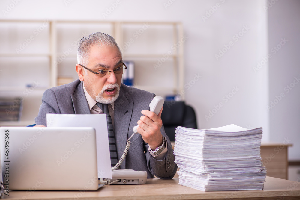Old male employee working at workplace Old male employee working at workplace