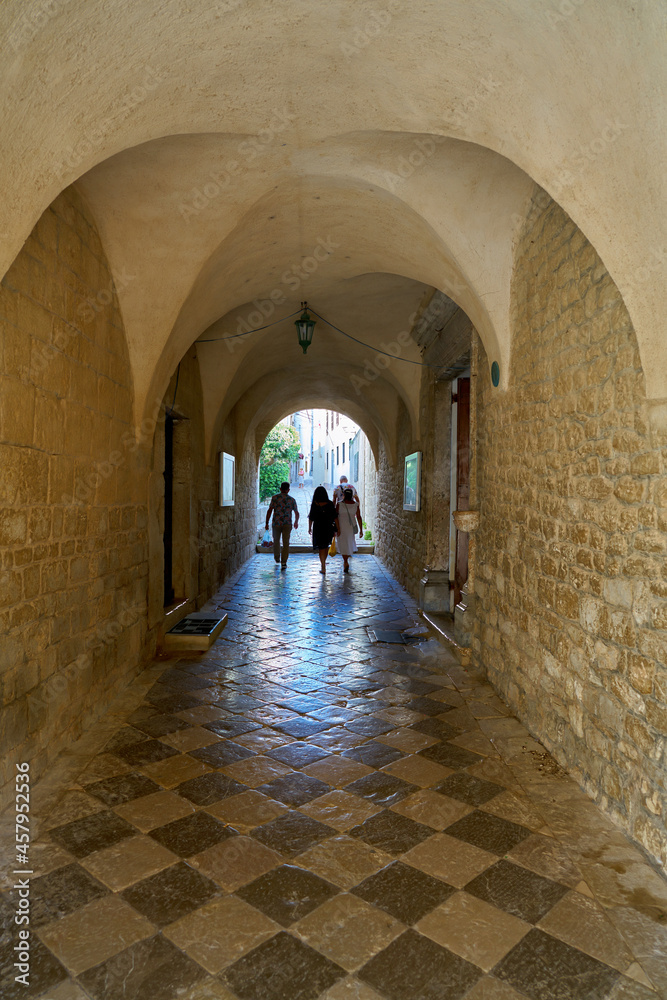 Tourists at a passage at the Cathedral of St. Quirinus in the old town of Krk in Croatia