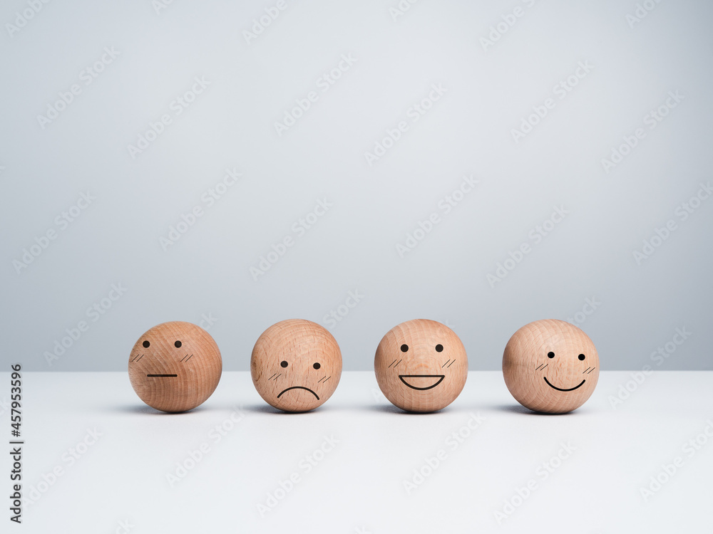 Customer service evaluation, feedback, and satisfaction survey concept. Wooden balls with a cute happy smiling emoticon with another emotional faces on white background with copy space. Customer service evaluation, feedback, and satisfaction survey concept. Wooden balls with a cute happy smiling emoticon with another emotional faces on white background with copy space.