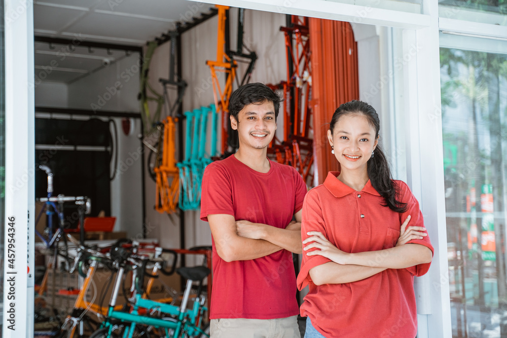 woman and man bicycle shop owner with folded arms standing in front of the shop