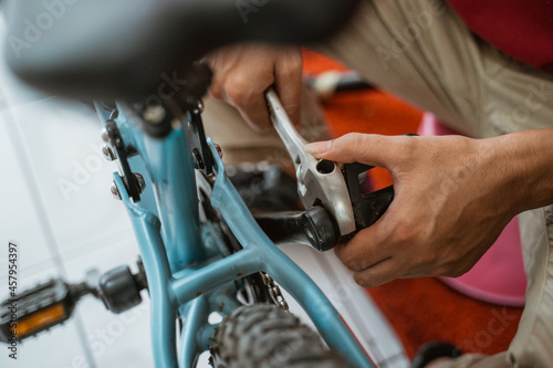 close up of a mechanic's hand installing a pedal using a wrench