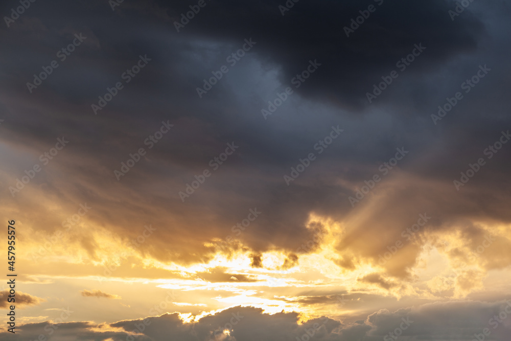 Colorful sunset or sunrise in the sky. The sun's rays are visible through the clouds. The sky and clouds are painted in different delicate colors. Beautiful background.