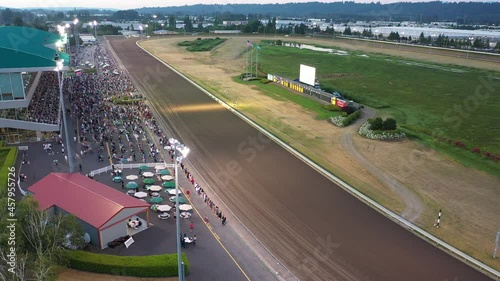 Cinematic 4K aerial drone footage of a horse race at Emerald Downs, a thoroughbred racetrack with a green grandstand in Auburn, Washington, near Highway 167 photo