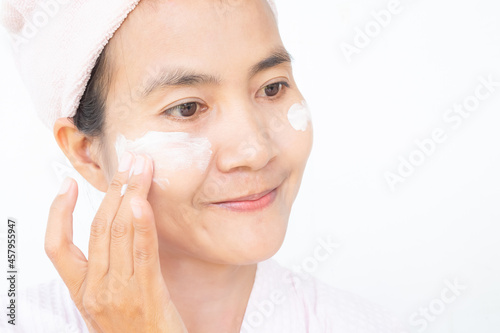 Woman applying lotion skin serum cream on face with smile after shower. Moisturizer skin care for moisturized reduce wrinkles and protection UV A, B. cosmetic for beauty and good health concept.