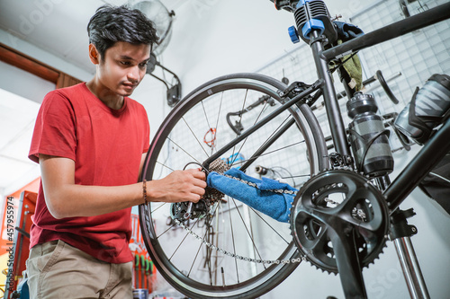 man in red clothes working fixing a trouble of the bicycle axle with a wrench