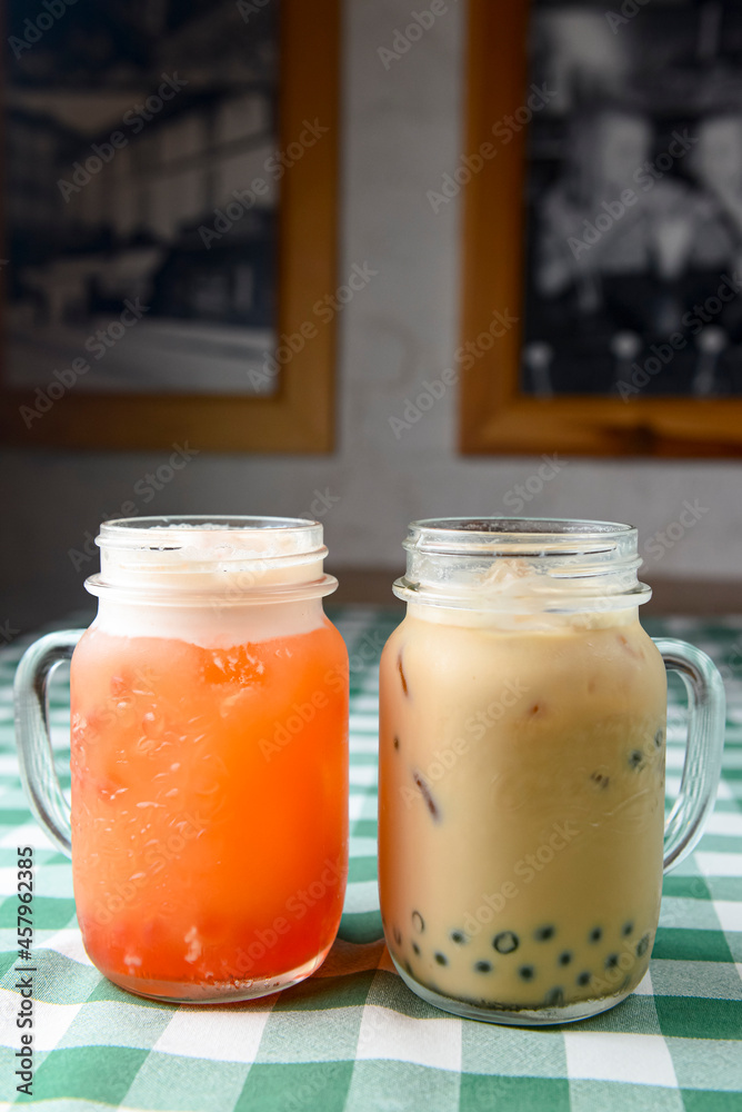 Row of fresh boba bubble tea glasses on wooden table with green plaid tablecloth background. Row of fresh boba bubble tea glasses on wooden table with green plaid tablecloth background.