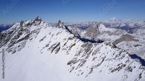 Aerial flight above stunning Alps Top Peak. 
Drone view above High mountain peaks sharp cliffs with blue sky , Val Thorens, France
 photo