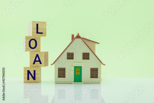Home equity loan, mortgage loan, financial concept : House model, wood cubes with a word loan on a table over light green background, depict borrowing or lending money to buy or purchase real estate