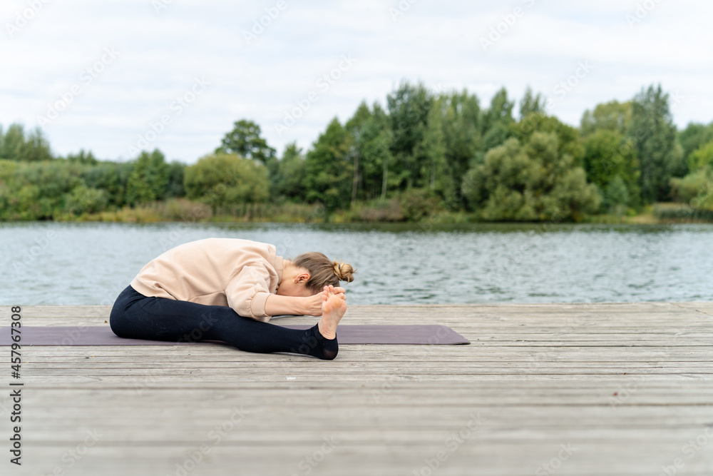 Woman warming up before yoga on a pier