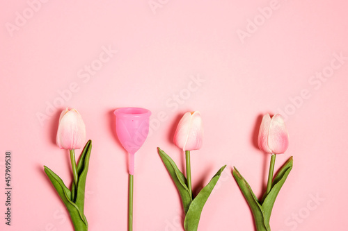 Tulips with menstrual cup as a flower on pink background. Eco-friendly reusable silicone, ecological alternative, zero waste concept. photo