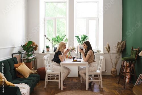 Mom, I can share everything with you. Mother and her daughter are sitting in the kitchen having a cup of tea and talking. © diignat