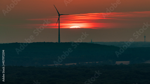 The setting sun and some wind turbines in the Ruhr Area, seen from the Halde Haniel, Bottrop, North Rhine-Westfalia, Germany