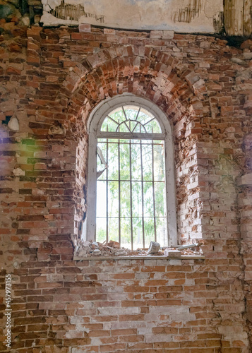 old arched windows in an abandoned church, iron grilles in front of the windows, crumbling window sills and window sills