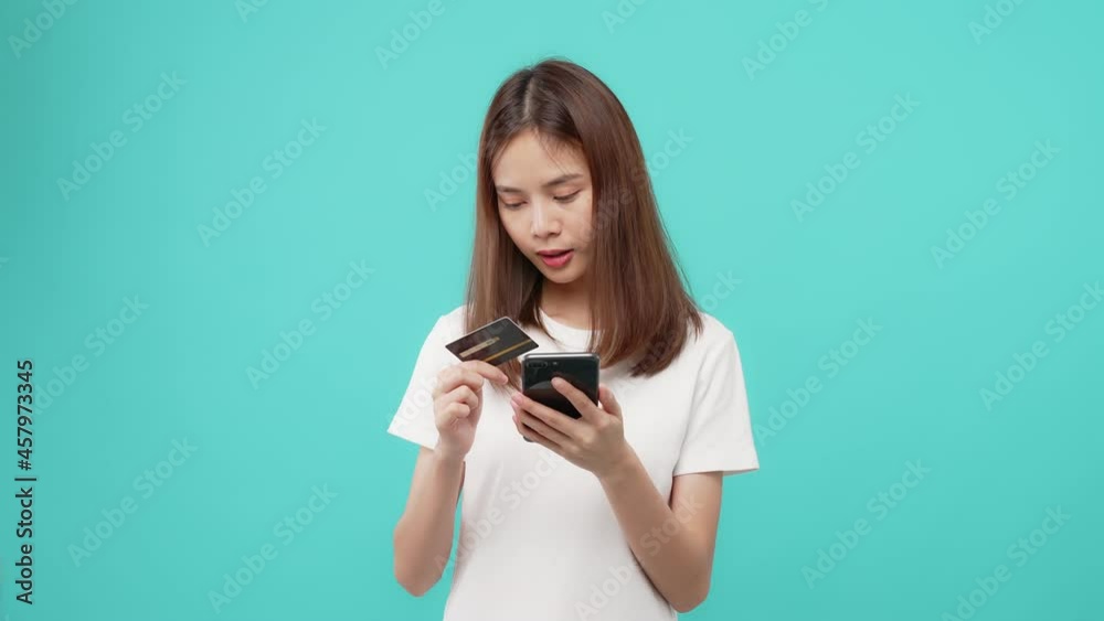 Beautiful Asian woman holding credit card and using smartphone for shopping online with payment on internet banking on the blue background. Beautiful Asian woman holding credit card and using smartphone for shopping online with payment on internet banking on the blue background.