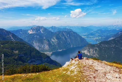 Traveler in sitting on a high mountain cliff enjoying scenery mountain top.