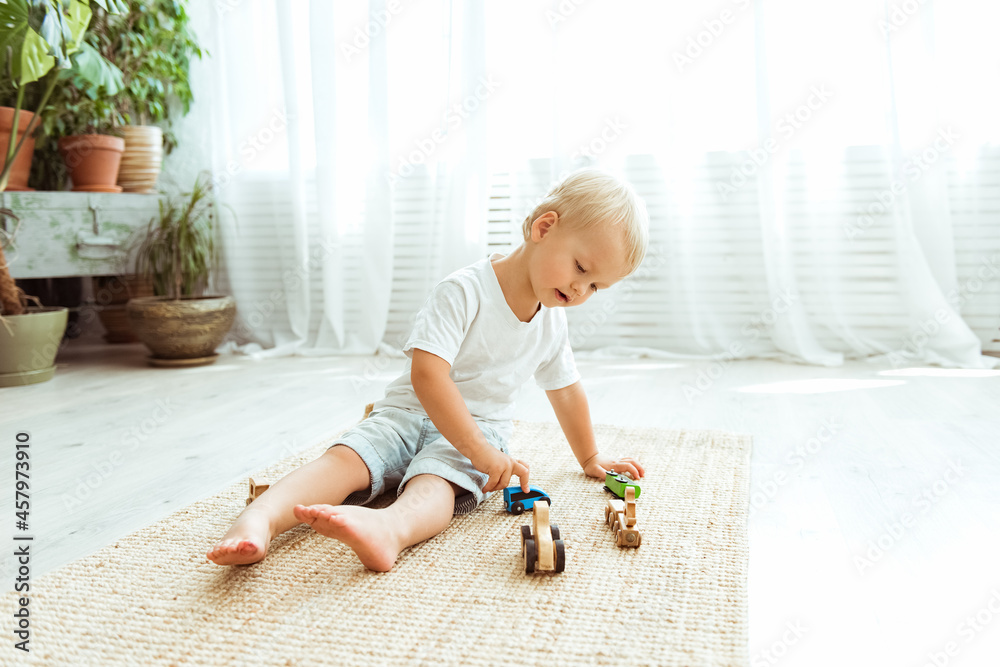 Preschool boy play with ecological wooden cars. Educational toys for preschool and kindergarten child. Child at home or daycare Preschool boy play with ecological wooden cars. Educational toys for preschool and kindergarten child. Child at home or daycare