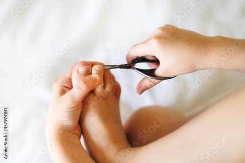 Kid girl cuts her toenails in bright real interior  lifestyle  hygiene and personal care  Child girl cuts her nails with scissors with copy space  top view. concept of children s independence