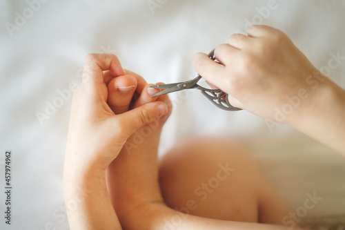 Kid girl cuts her toenails in bright real interior, lifestyle, hygiene and personal care, Child girl cuts her nails with scissors with copy space, top view. concept of children's independence