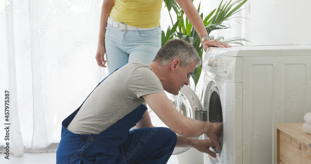 Technician repairing a washing machine at home Technician repairing a washing machine at home