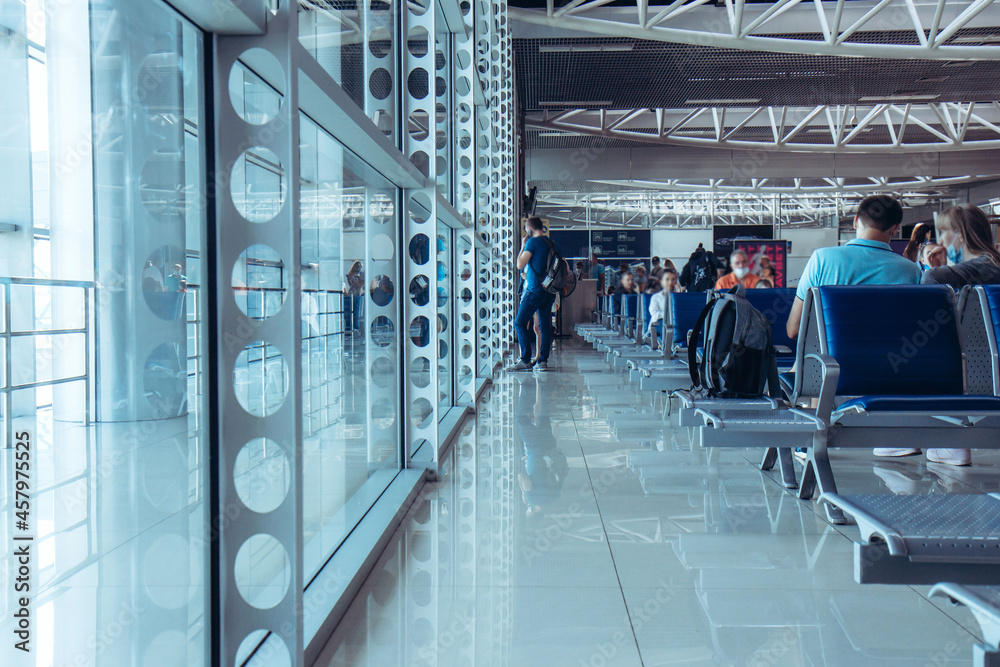 Fototapeta premium Passengers in the airport terminal. People waiting to board a flight at the airport. Blurred people in the background.