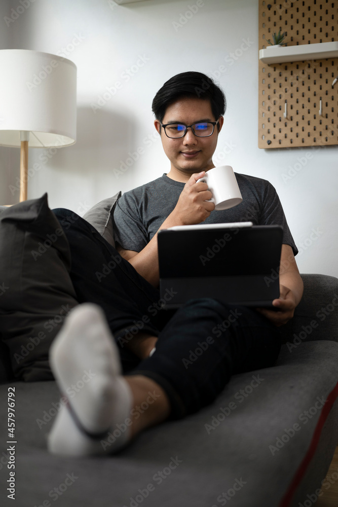 Casual man holding coffee cup and using computer tablet on couch. Casual man holding coffee cup and using computer tablet on couch.