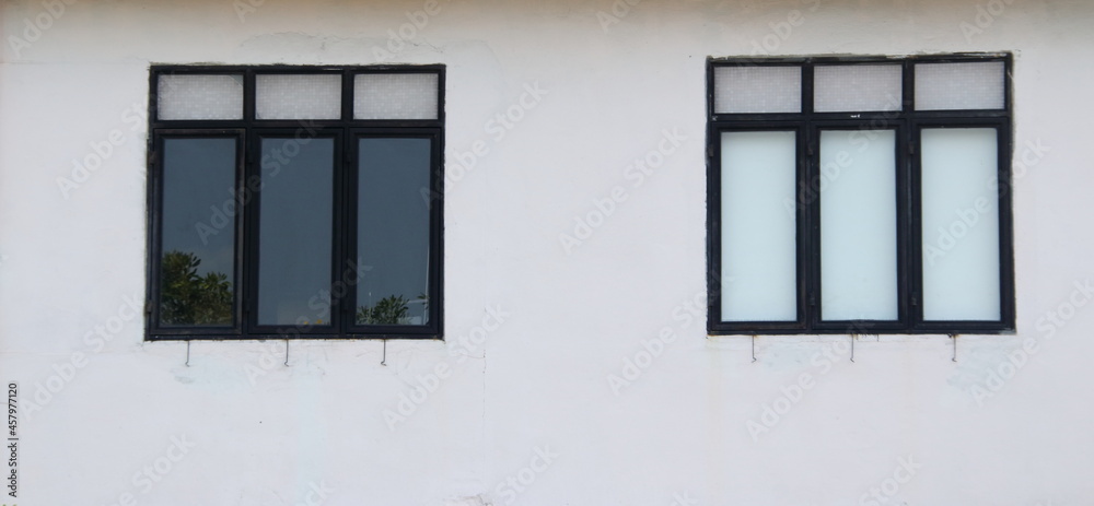 Triple mirror window in painted black aluminium frame on white painted wall of building. Triple mirror window in painted black aluminium frame on white painted wall of building.