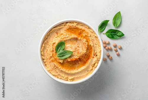 Hummus with olive oil, spices and basil on a light gray background. Vegetable, oriental dish.