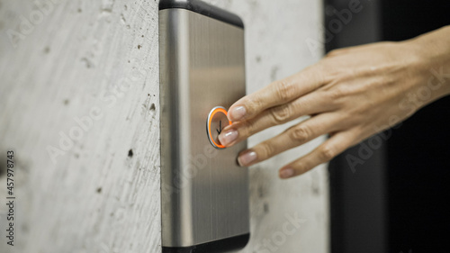 Female hand pressing elevator button, woman in office building, destination