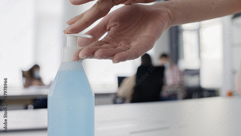 Female using hand sanitizer at work, covid-19 precautions, disinfectant spray