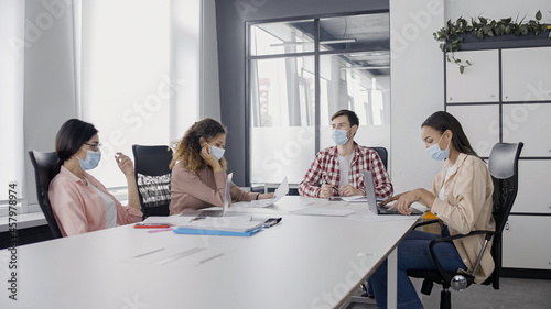 Young business people wearing protective masks during work meeting, pandemic