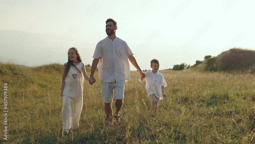Father with son and daughter walking on summer field Father with son and daughter walking on summer field