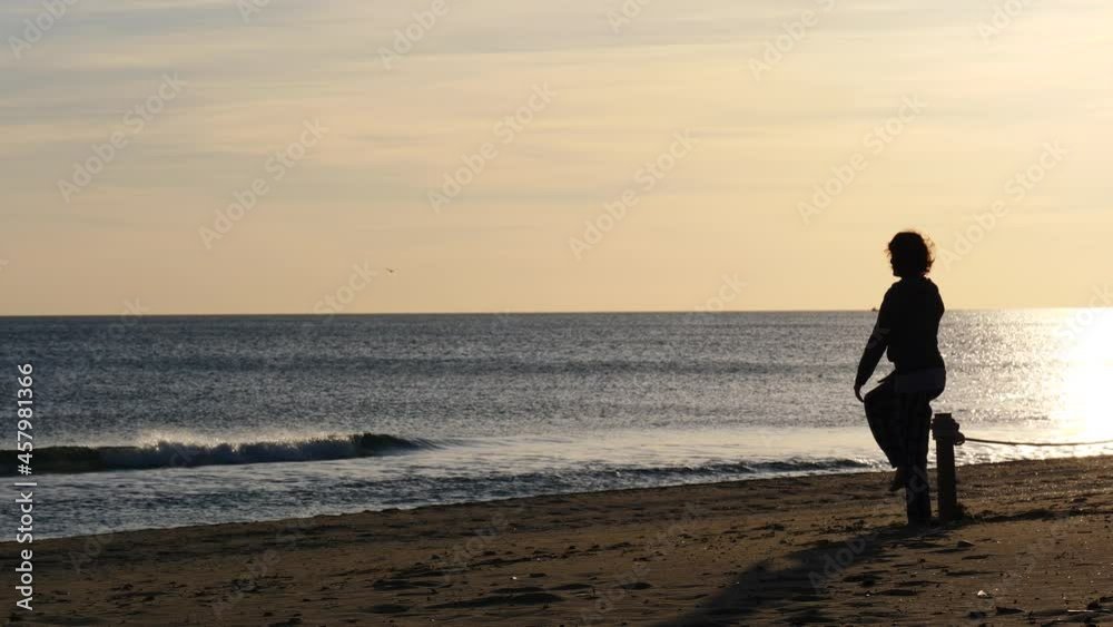 Woman in pajamas barefoot at morning time on beach. Female exercising, doing sports outdoors. Camping on nature. Slow motion. Woman in pajamas barefoot at morning time on beach. Female exercising, doing sports outdoors. Camping on nature. Slow motion.