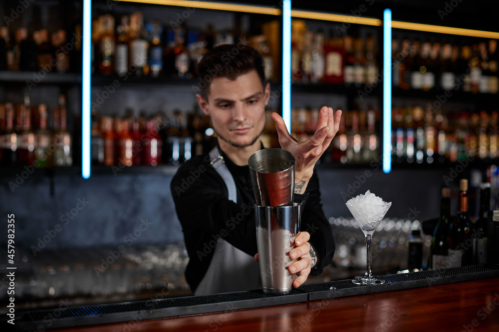 barman shaking tasty cocktail at the bar