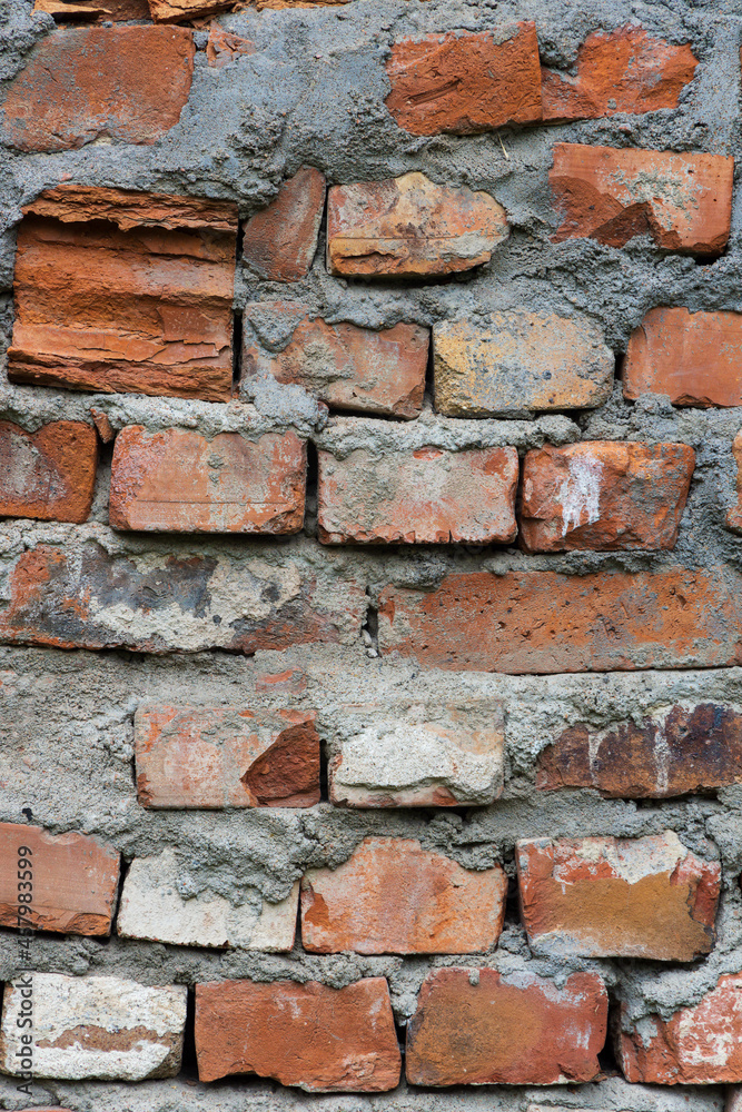 Lot of bricks in the wall and between them thick layers of cement close-up vertical orientation Lot of bricks in the wall and between them thick layers of cement close-up vertical orientation