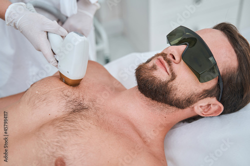 Beauty salon customer undergoing a laser chest hair removal photo