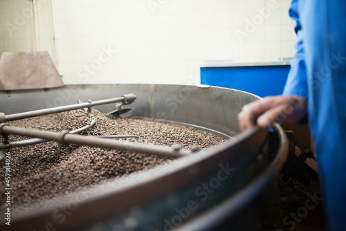 Close-up of coffee roasting process. Interior of coffee production workshop with set up roasting equipment. Production, food concept