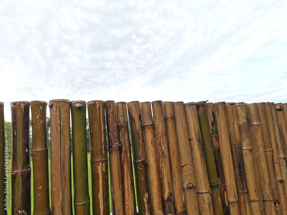 Obraz premium Strong bamboo fence against clouds in the sky