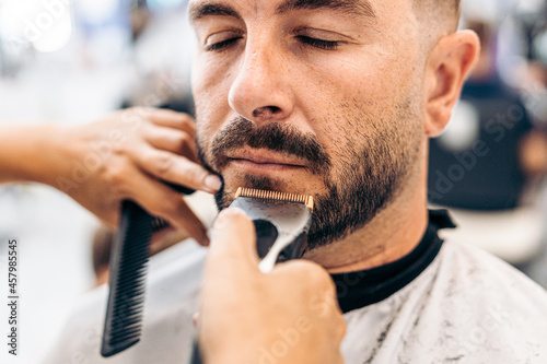Portrait of a man with eyes closed being shaved in a barbershop