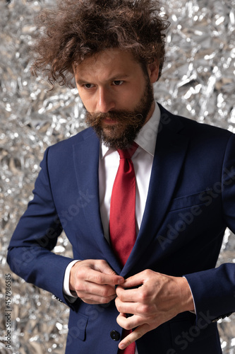 handsome businessman closing his jacket and looking away photo