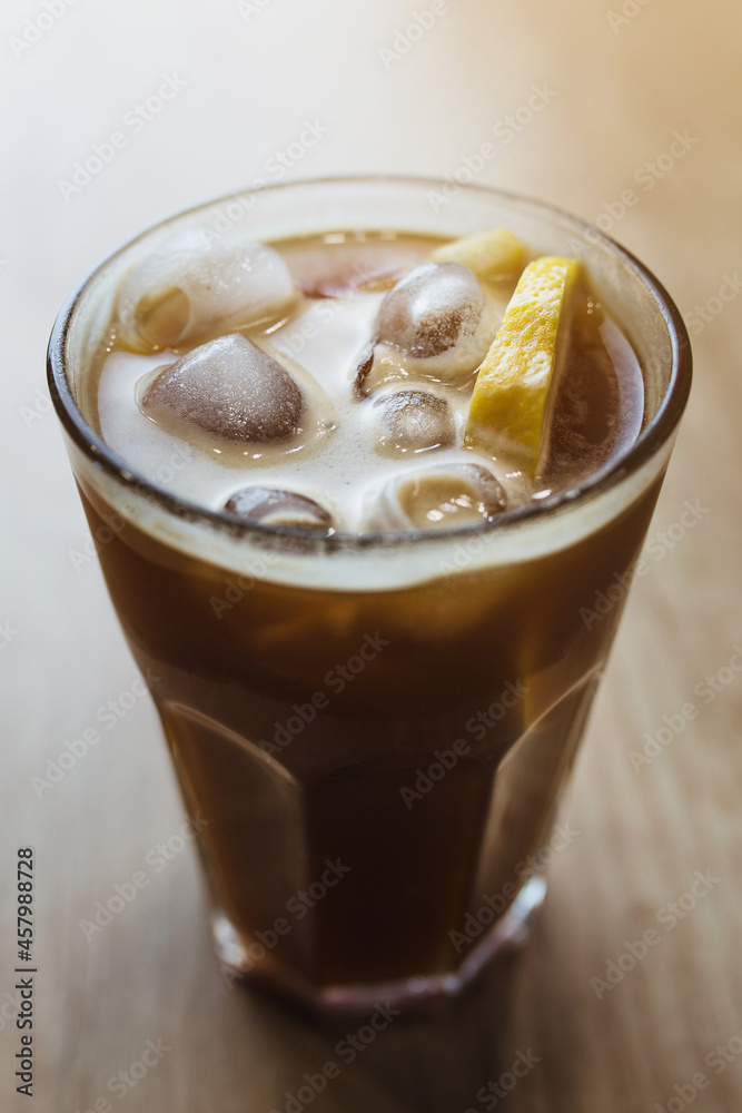 Iced coffee in a glass with ice and lemon - a summer drink for vivacity Iced coffee in a glass with ice and lemon - a summer drink for vivacity