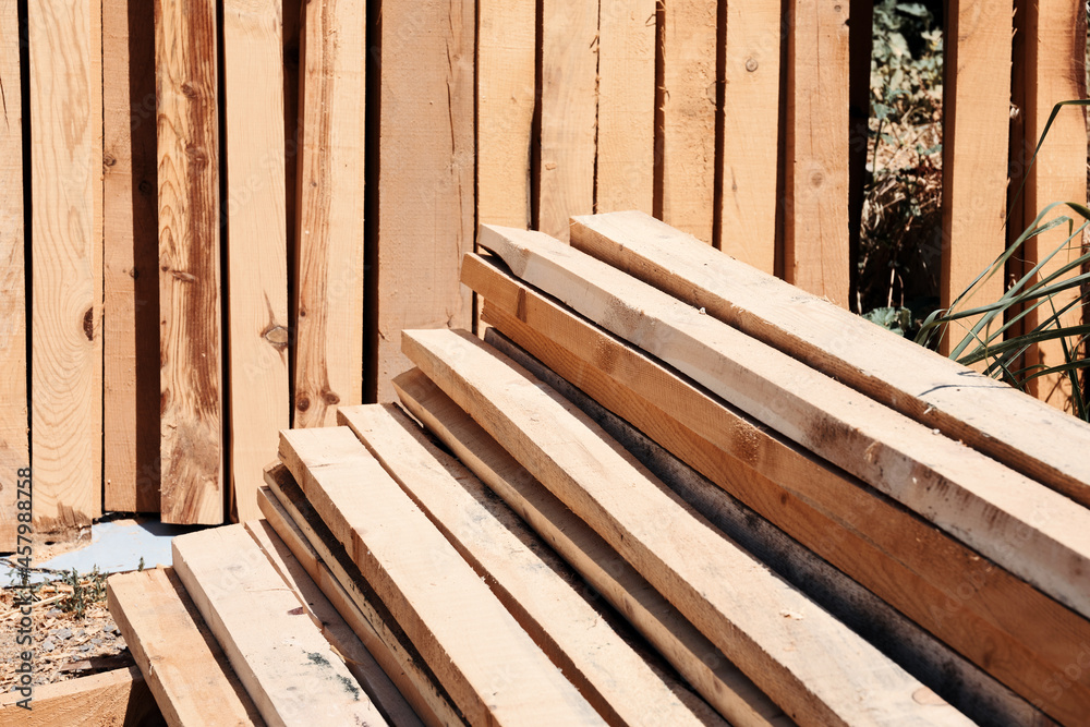 Stack of sawed wooden planks or timber at a construction site.