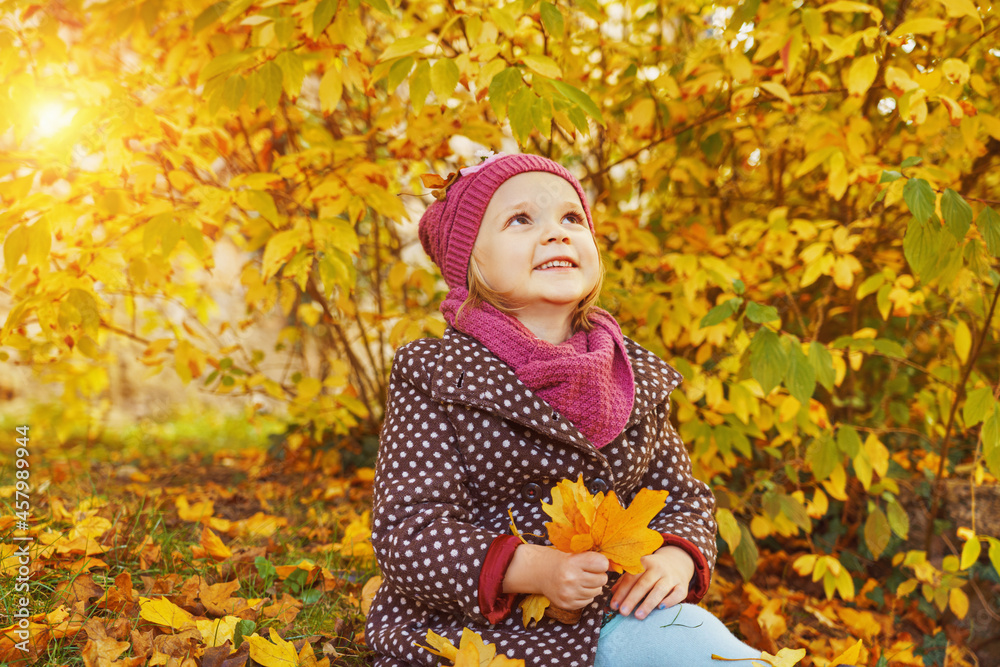 Kids play in autumn park. Children throwing yellow leaves.