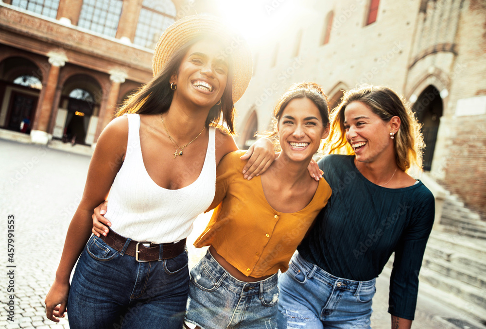 Three young diverse women having fun on city street outdoors - Multicultural female friends enjoying a holiday day out together - Happy lifestyle, youth and young females concept