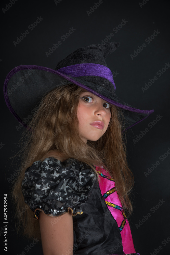 A girl dressed as a witch and a wide-brimmed hat for Halloween. A girl dressed as a witch and a wide-brimmed hat for Halloween.