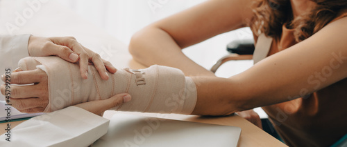 Close up of orthopedic doctor investigates woman patient broken arm covers with a splint plaster cast. Trauma can happen after people fall and are hurt physically by accidents. Rehab center services. photo