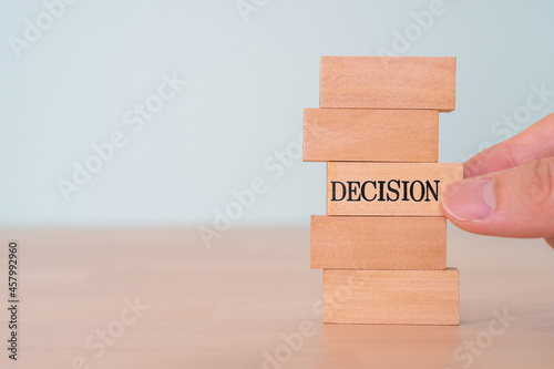 「DECISION」と書かれた積み木を手で引き抜こうとしている人 photo